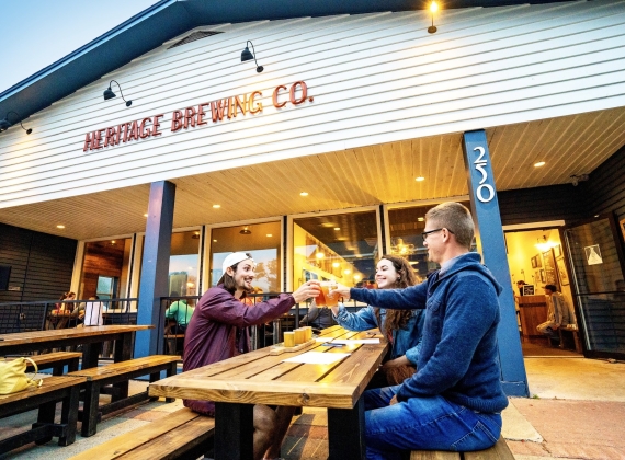 A group toasting their beverages at Heritage Brewing Co.
