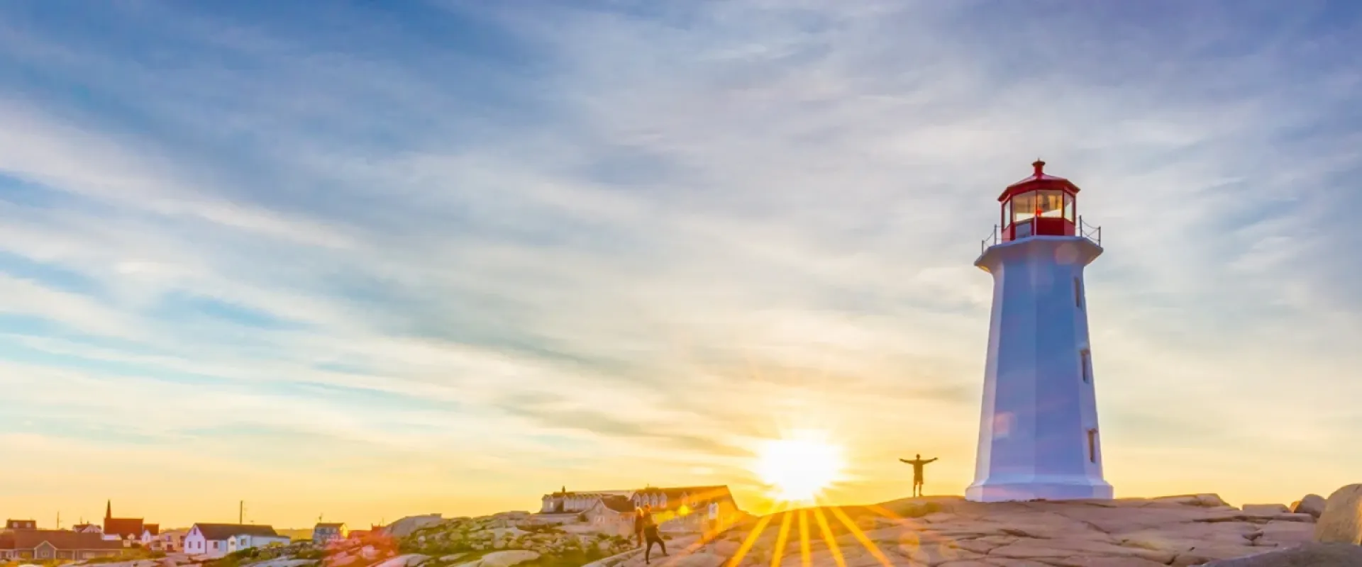 Visitors pose under the Peggy's Cove Lighthouse at dusk